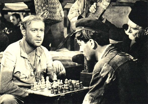 Узники фашистского концлагеря играют в шахматы с помощью фигур, вылепленных из белого и черного хлеба. Кадр из югославского фильма 'Кампо Мамуля' (1959г.)